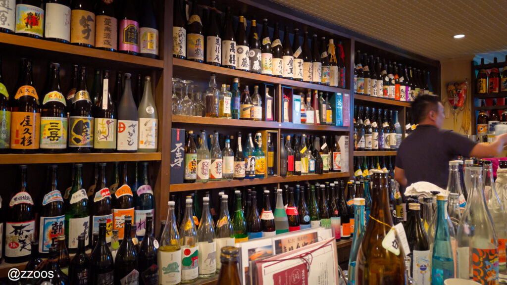 カウンター奥に並ぶ大量の焼酎ボトルと賑やかな店内の雰囲気