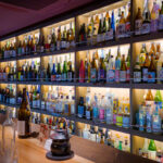 Shelves at Shochu Bar ROKU with mostly small shochu bottles and almost no 1.8-liter isshobin bottles.