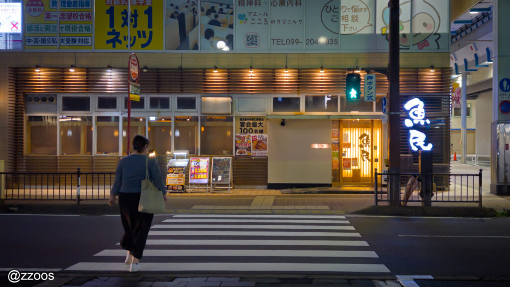 夜の踏切を渡る通行人の姿