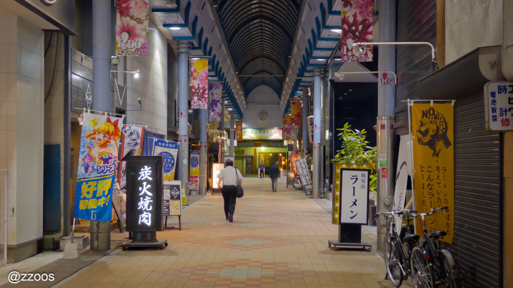 夜の日本の商店街。歩く人と明るい看板