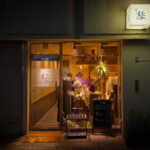 Exterior of Sushi Kaoru showing the entrance and sign at night.