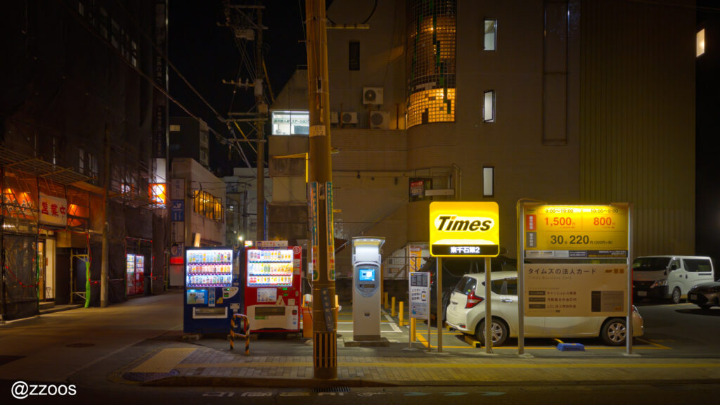  夜の鹿児島の街。駐車場と自動販売機が並ぶ裏路地。