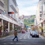 Street view in Kagoshima with people crossing a crosswalk at night.