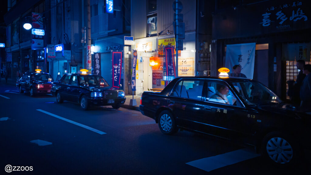夜の路地で客を待つタクシーの様子。