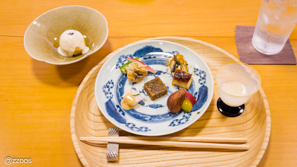 甘酒と前菜プレート、複数の小皿料理が並ぶ一皿