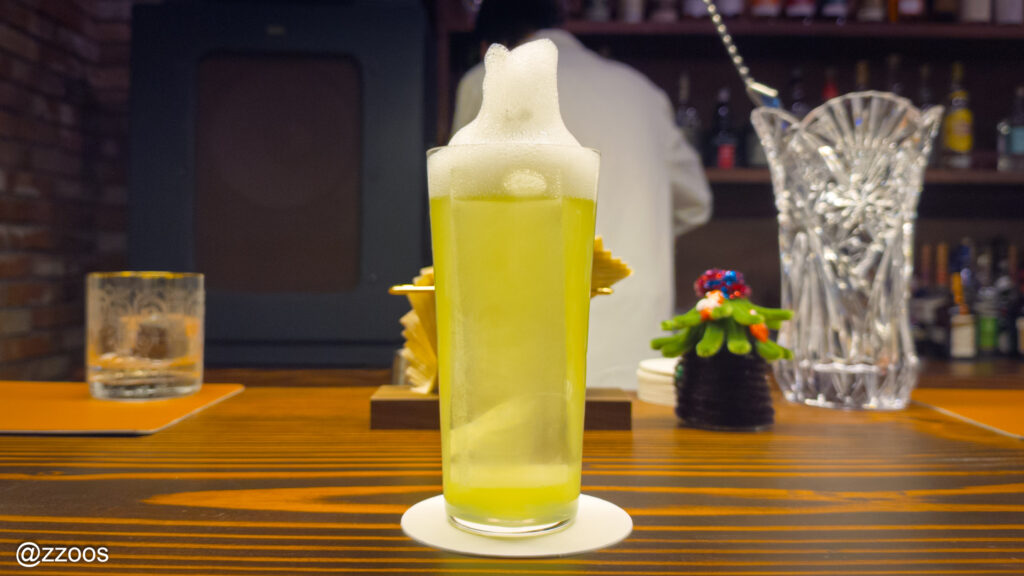細長いグラスに泡をのせたカクテル