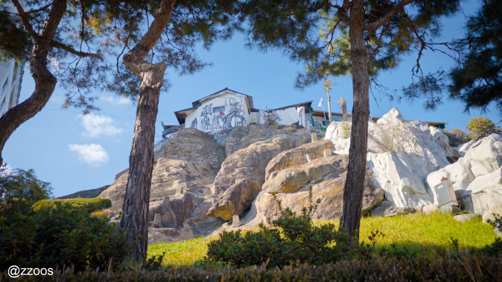 松の木の裏、岩の丘の上にある不思議な建物