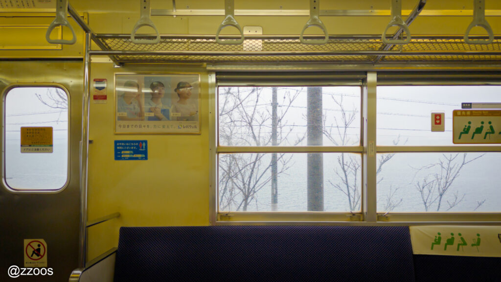 The interior of an old train. The sea visible outside the window.