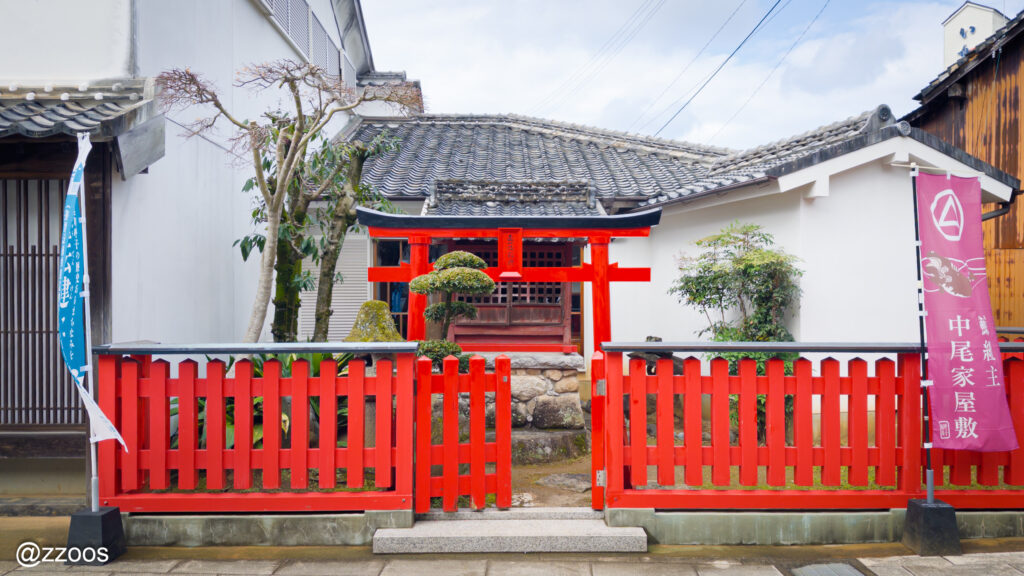 赤い塀と鳥居がある小さな稲荷神社