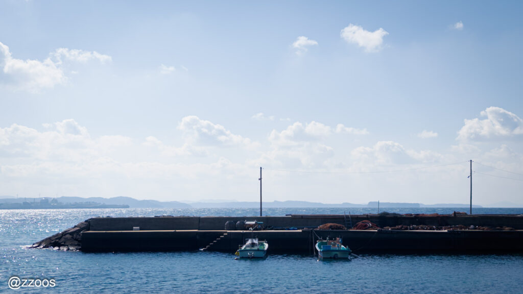 The distant horizon and sky, and two small boats.