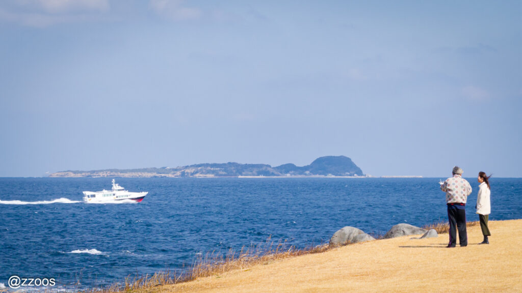 The sea, a passenger boat, and a couple.