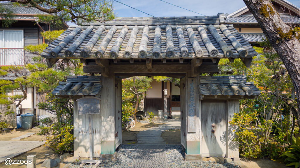 The entrance of Mizuno Ryokan in front of the stone wall path.