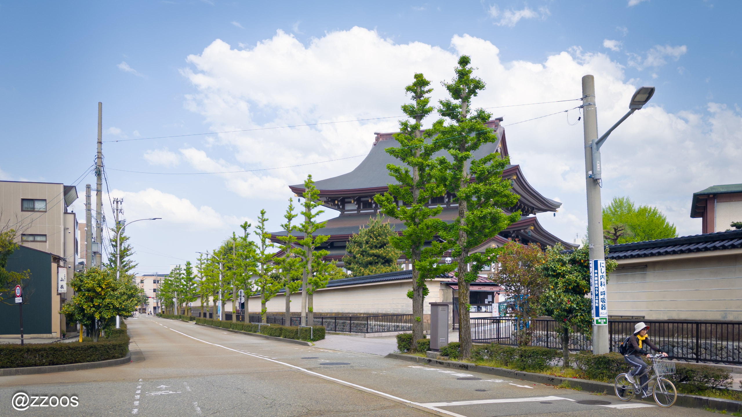 A street in Kanazawa with a traditional building and a cyclist