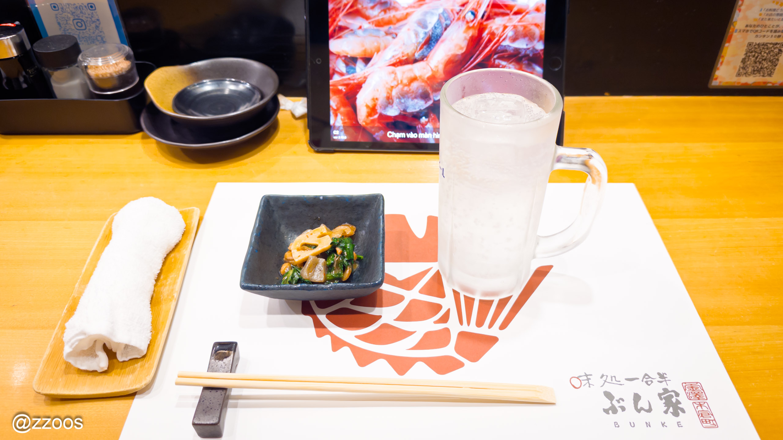 Oshibori, otoshi, and Kurokiri-shima soda highball on the table at Ichigohan Bunke, with the order tablet visible in the background