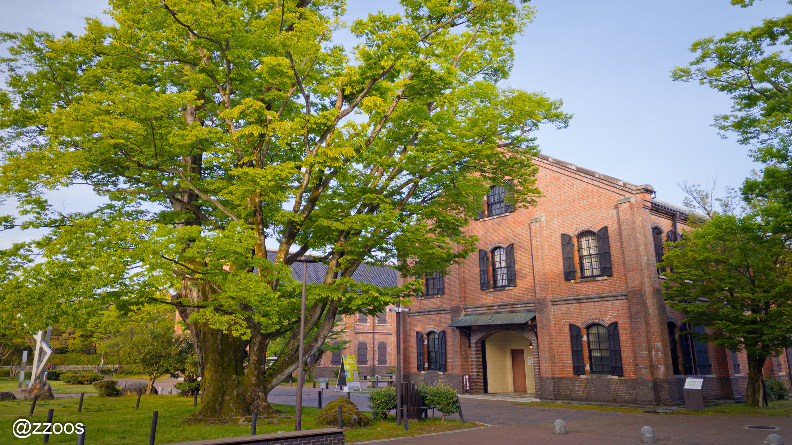 Red brick building and large tree with gabled roof in Honda-no-Mori Park