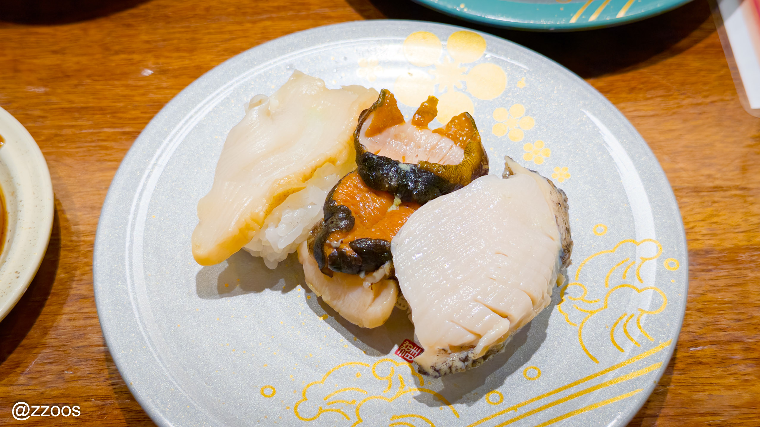 A plate of three types of shellfish sushi, including abalone and conch