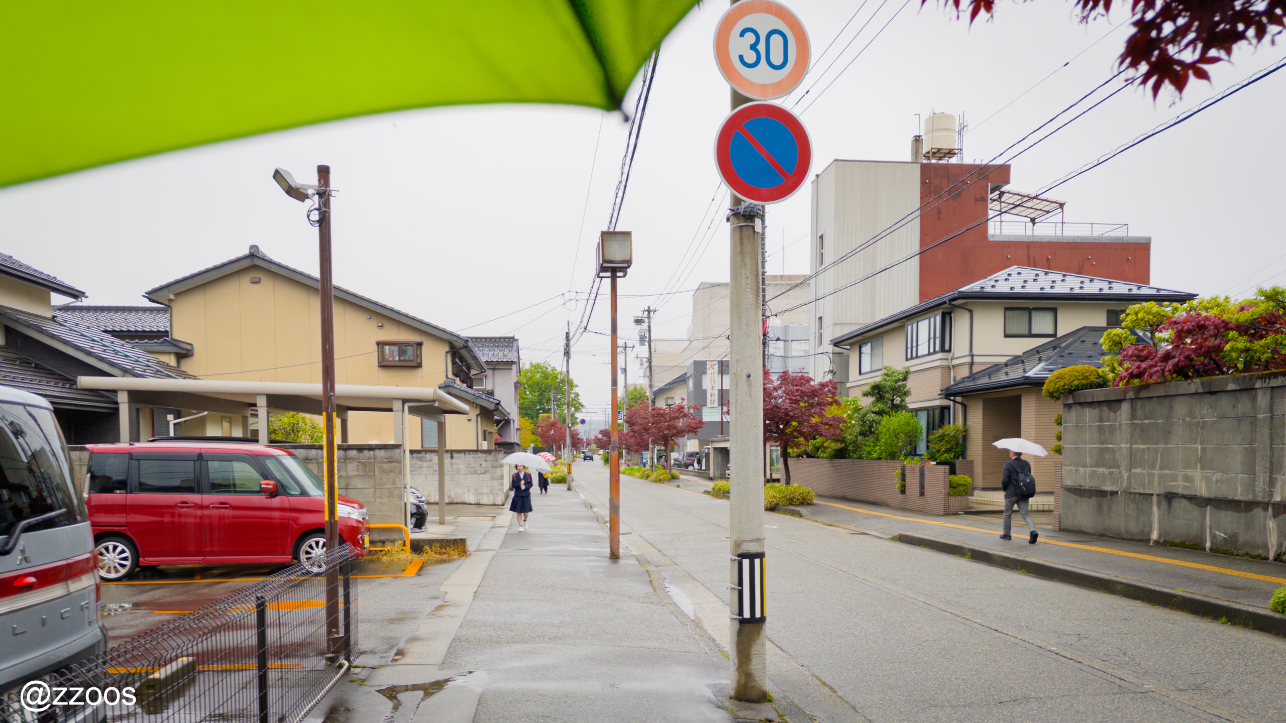 雨の富山の街を傘をさして歩く様子
