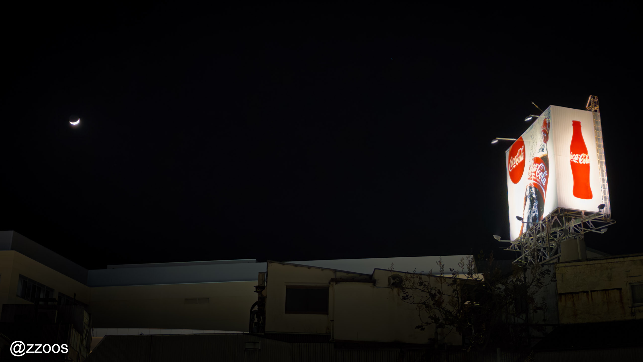The moon and a Coca-Cola sign in Kanazawa's night sky