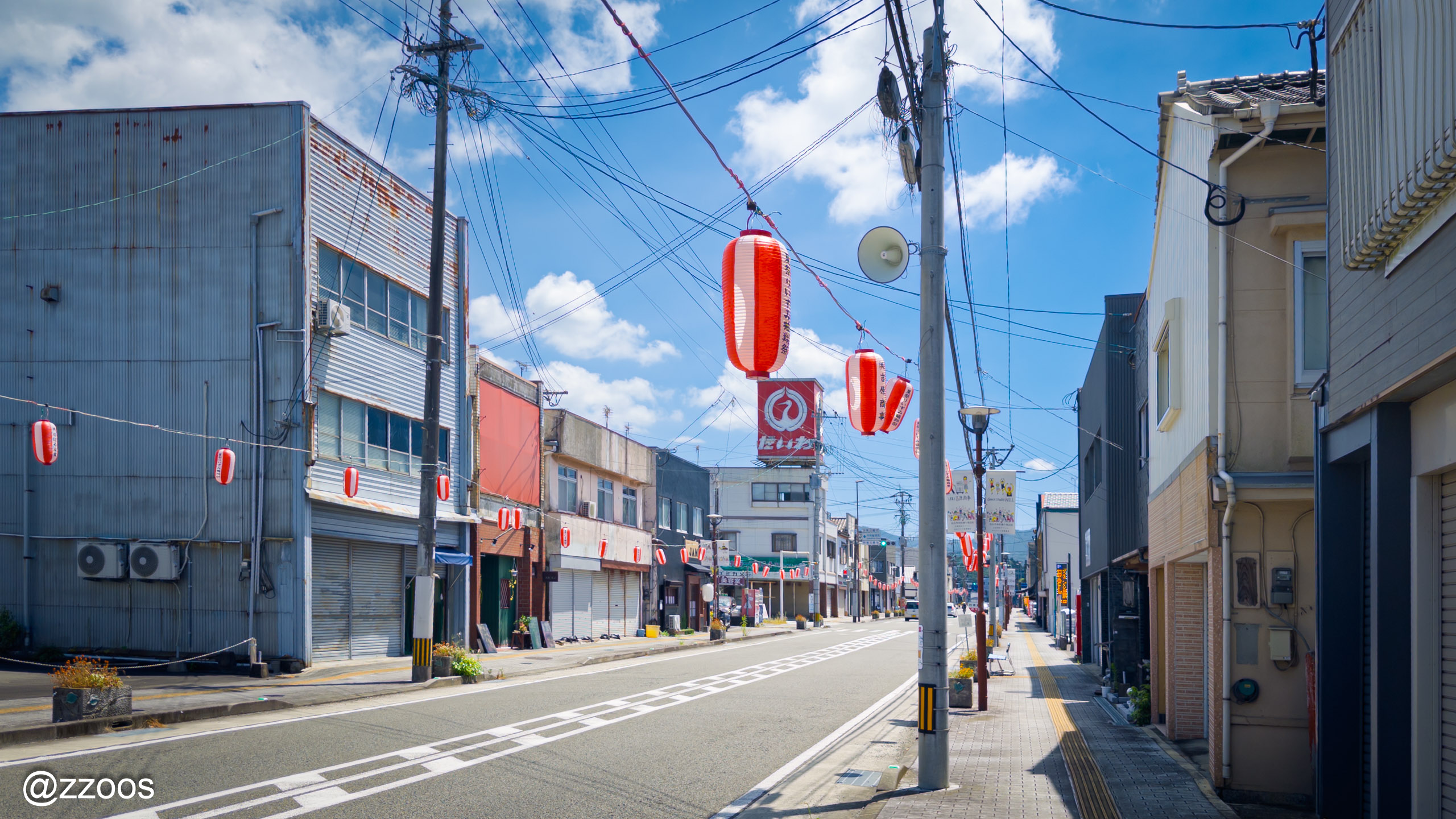 Festival lanterns strung over Honmachi street under a blue sky