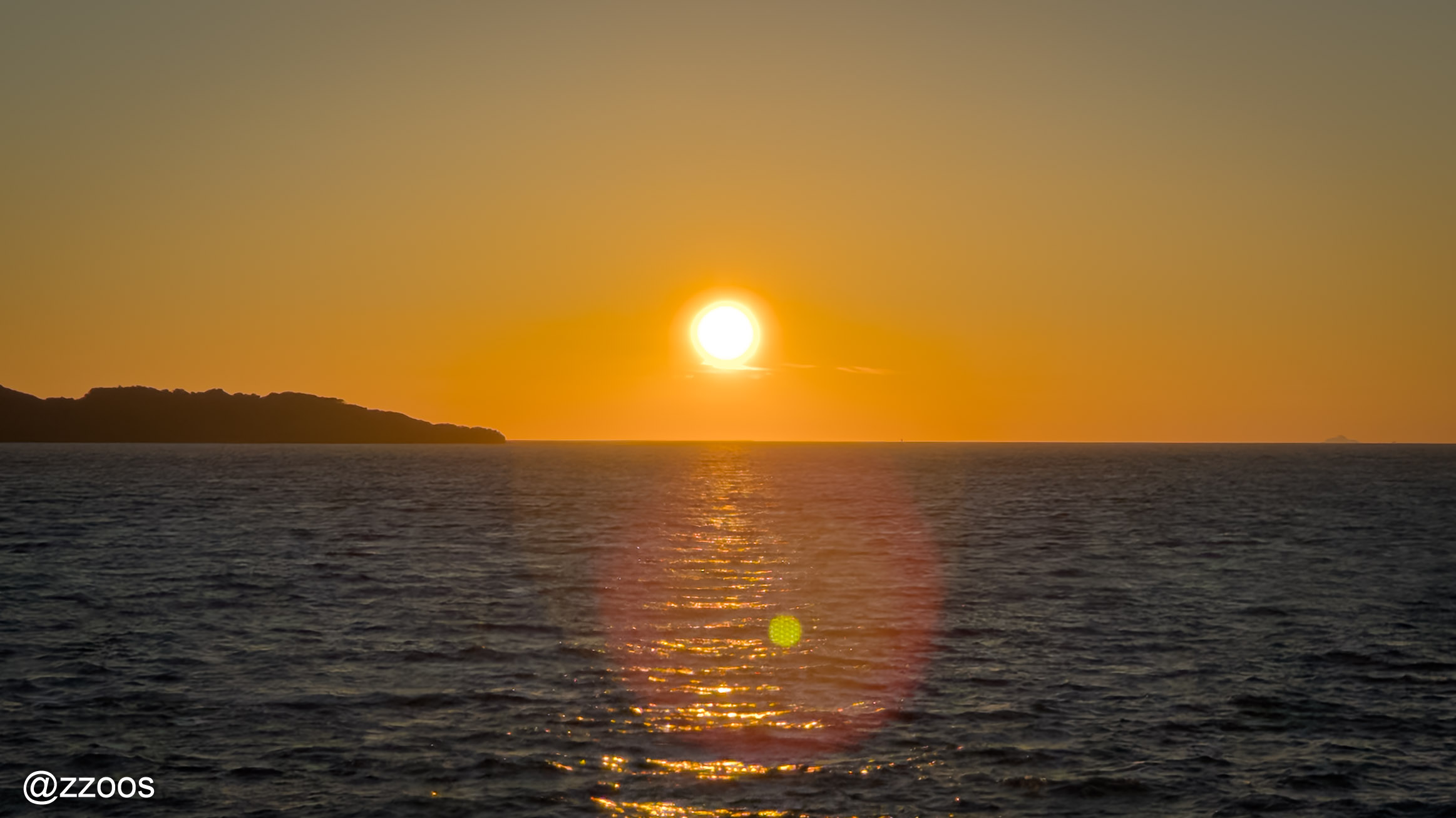 水面に近づきながら赤く大きくなる太陽
